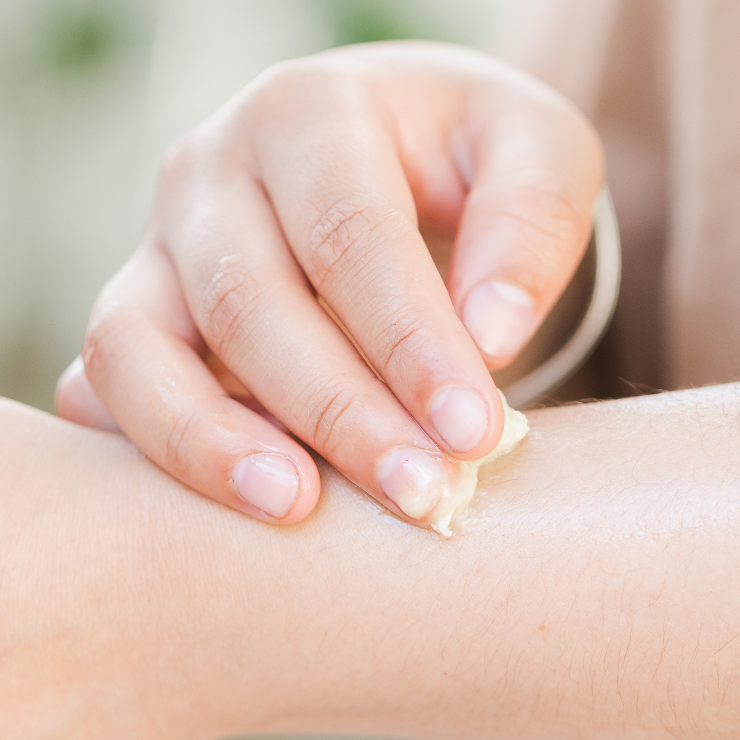 Hand applying oatmeal salve to a child's arm 